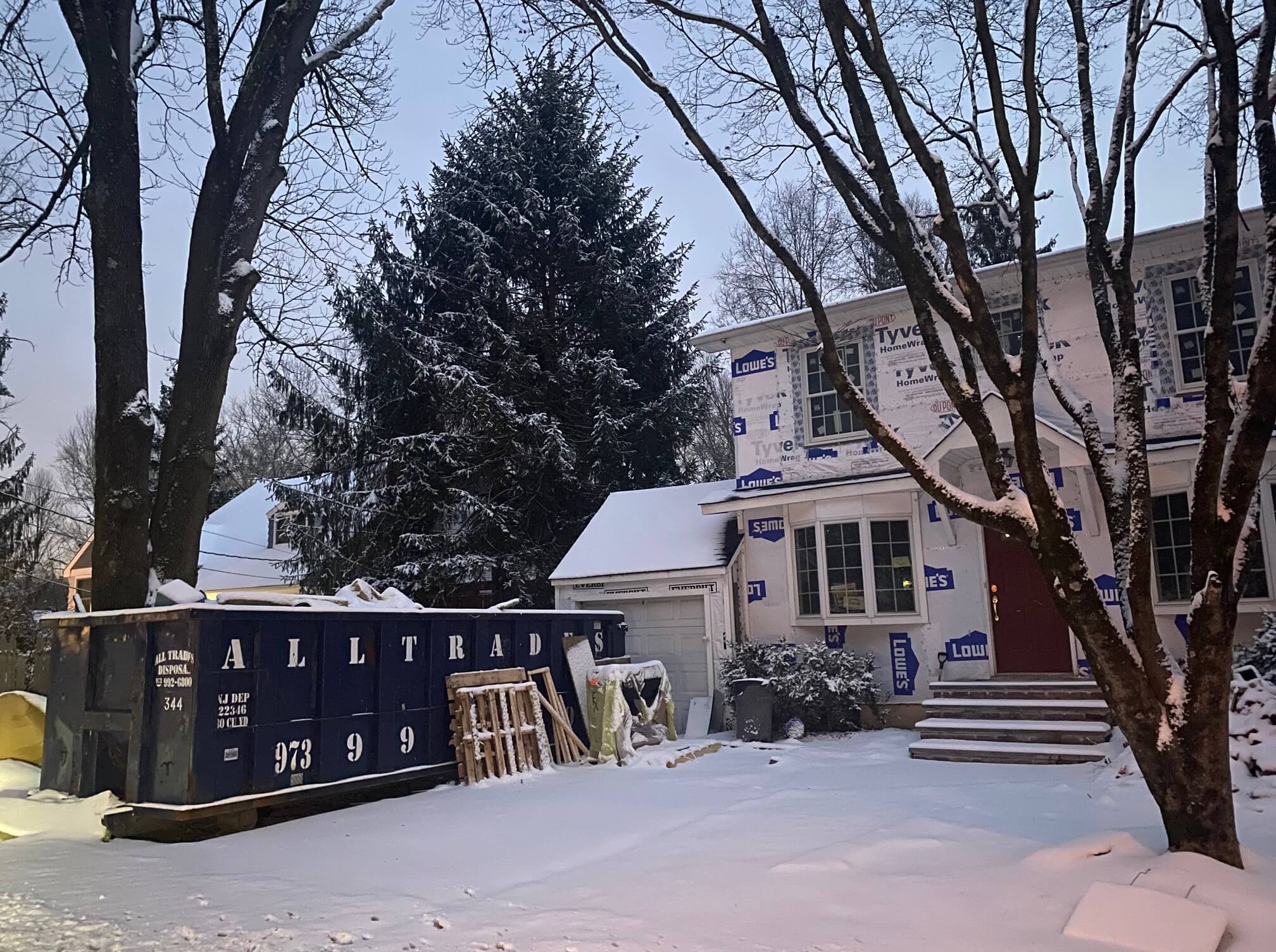 All Trades Disposal Dumpster in the Snow, shown on a page with frequently asked questions about dumpsters